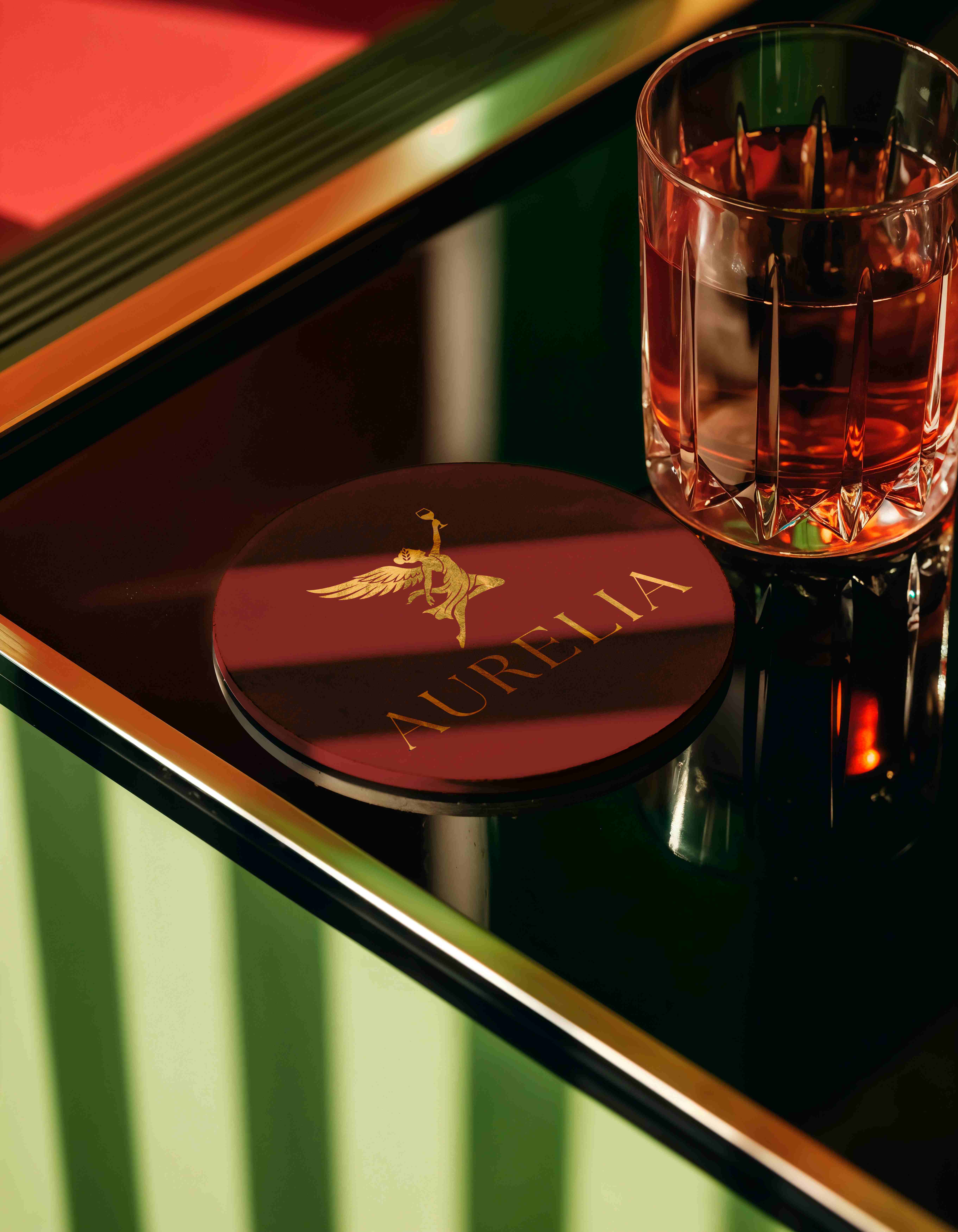 An Aurelia coaster beside a crystal glass of amber spirit